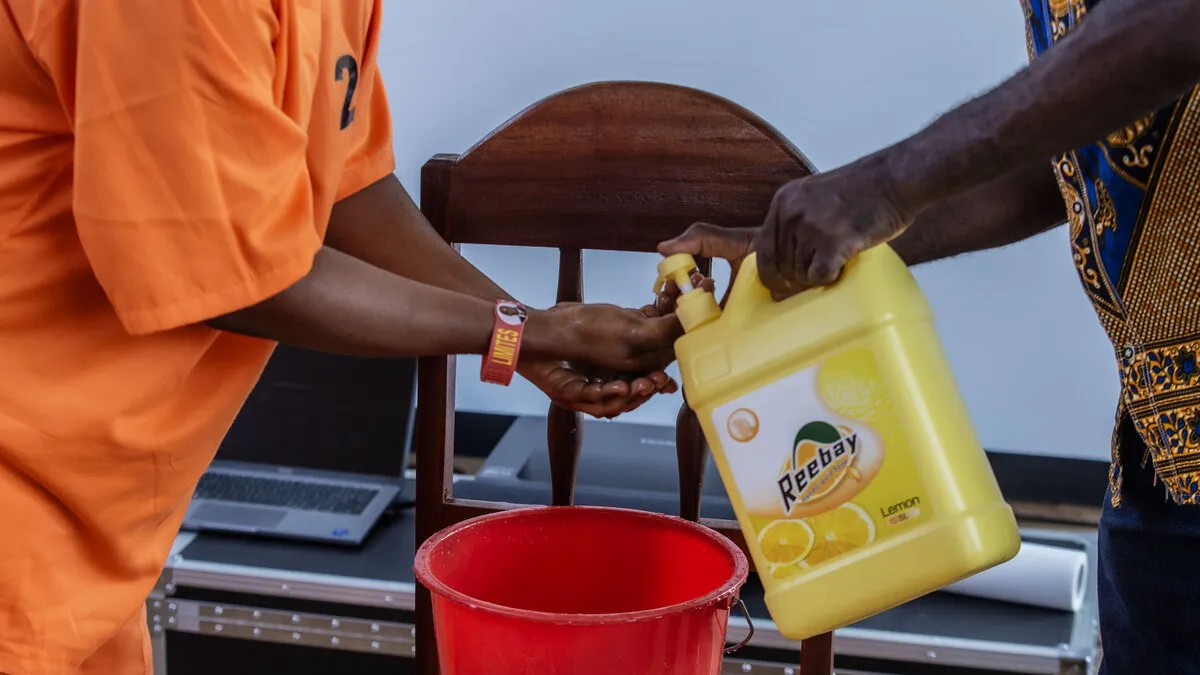 Une personne en combinaison orange se lave les mains