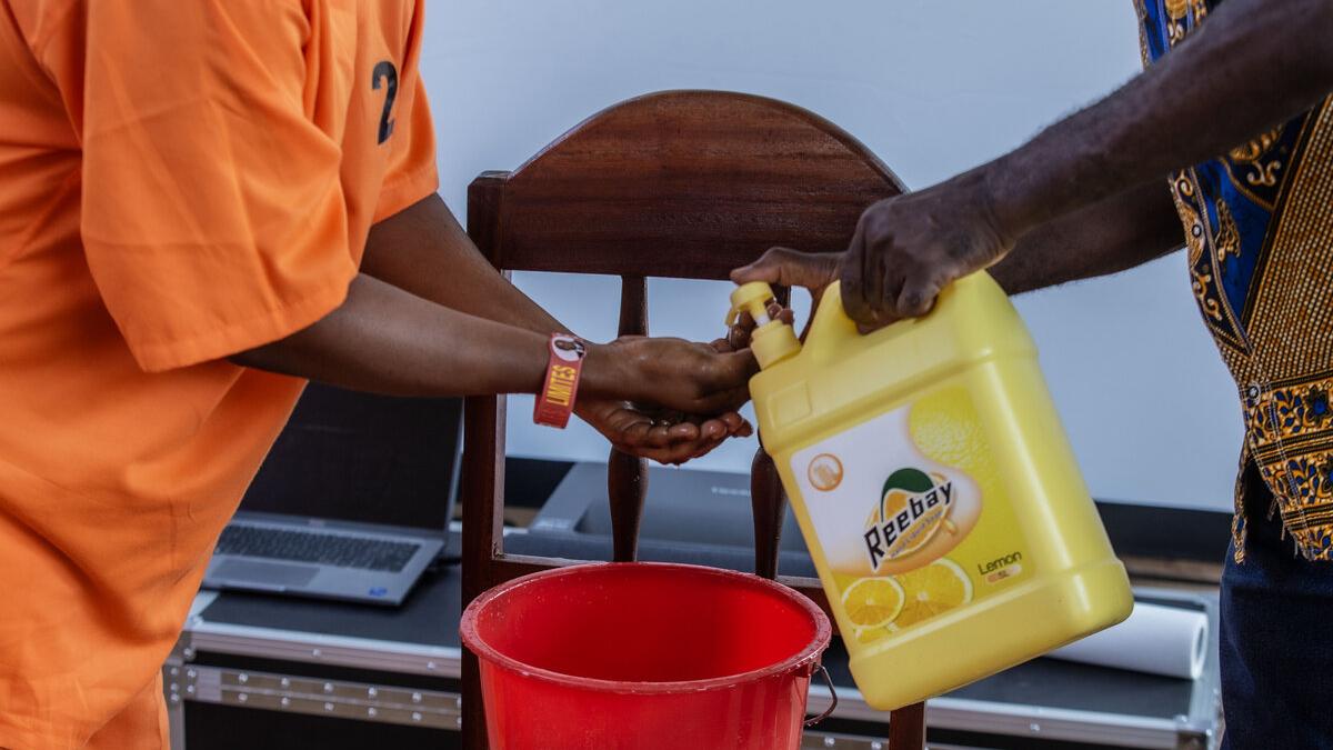 Une personne en combinaison orange se lave les mains