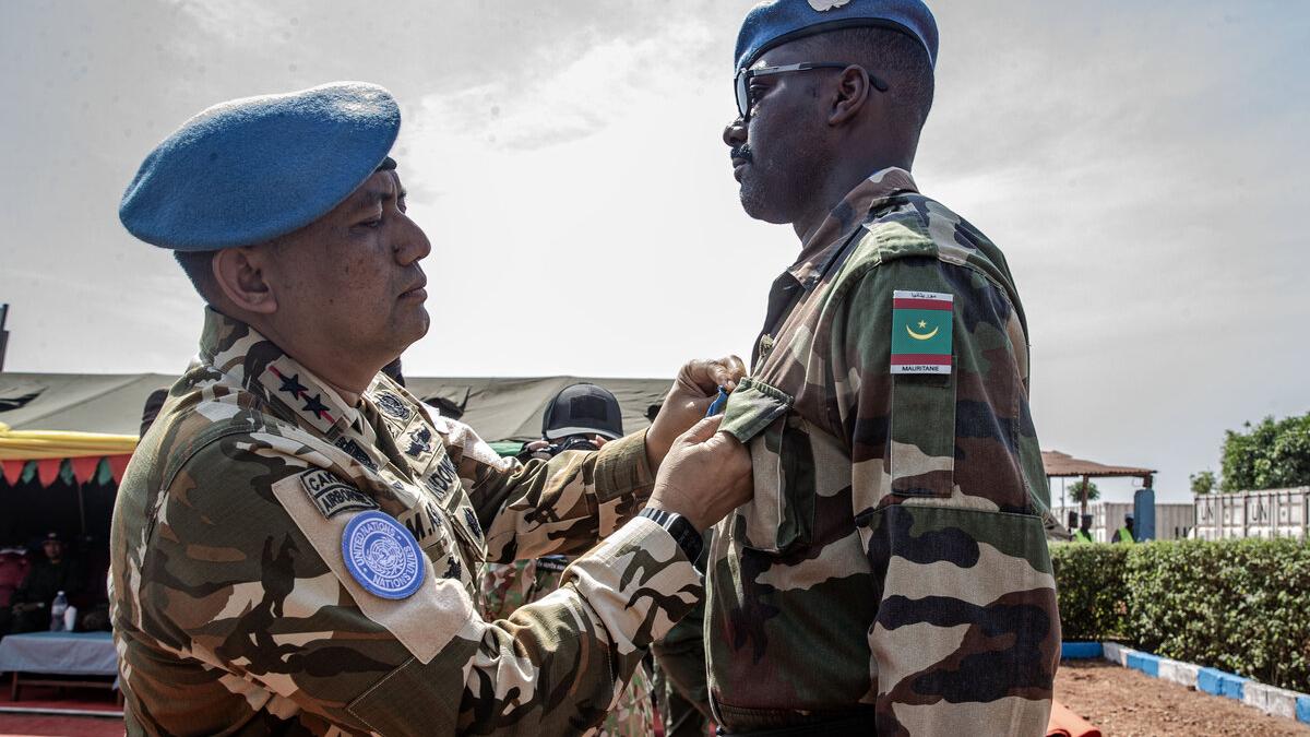 Un homme en uniforme militaire épingle une médaille sur un autre homme en uniforme militaire.