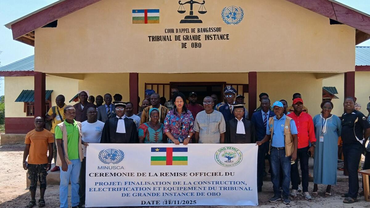 Un groupe de personnes se tient devant un bâtiment, brandissant une grande banderole.