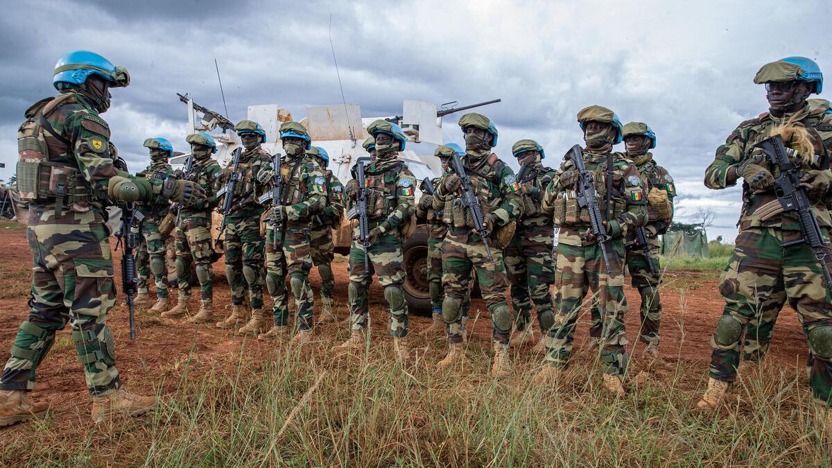 Un groupe de Casques bleus armés de l'ONU se tient en rang, à l'extérieur de leur véhicule.