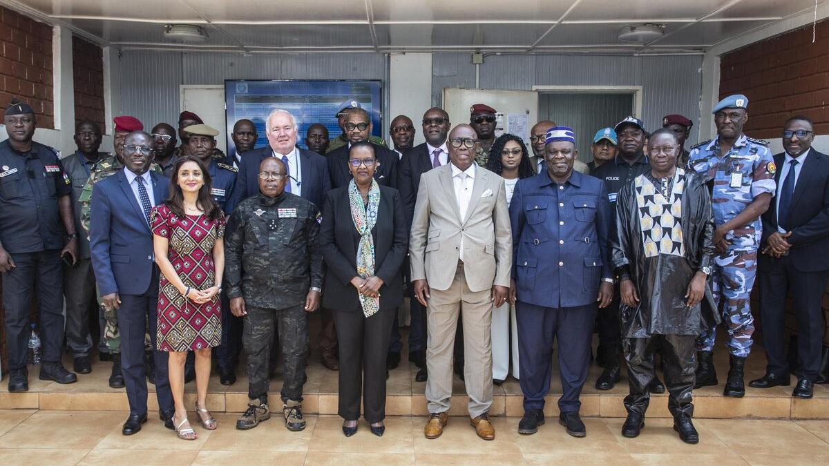 Un groupe de personnes en tenue militaire et civile se tient en rangs pour une photo