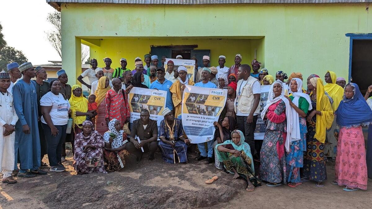 Un groupe de personnes pose pour une photo devant un bâtiment, tenant une banderole
