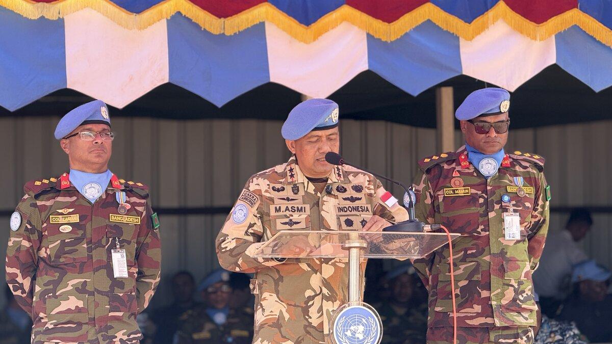 Un casque bleu parle à un public depuis un podium. 