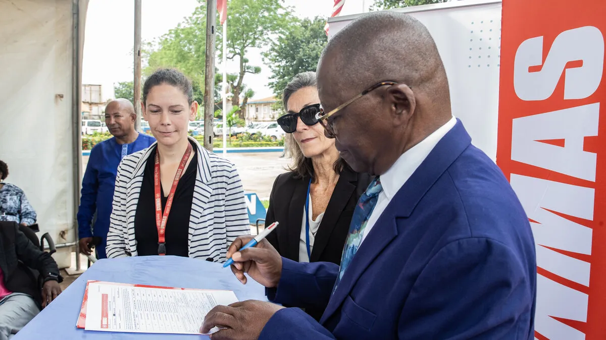 Le président de COMNAT‑ALPC signe un document. 
