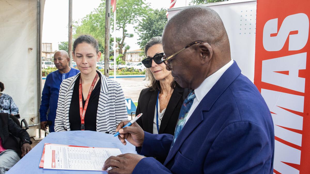 Le président de COMNAT‑ALPC signe un document.