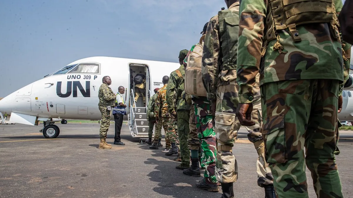 Des Casques bleus font la queue pour monter à bord d’un avion de l’ONU.