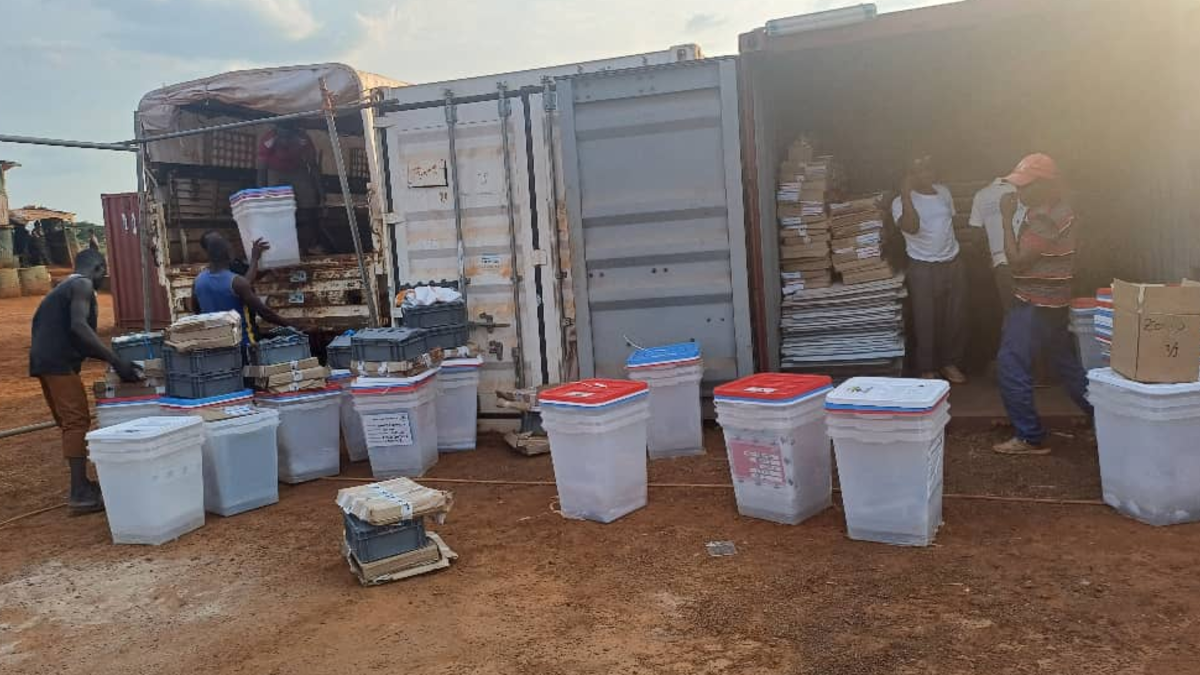 Un groupe de personnes manipule des cartons contenant du matériel électoral.