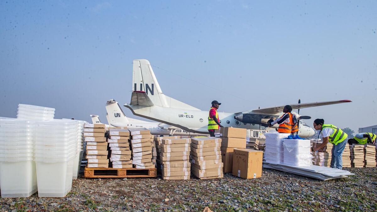 Des travailleurs trient des fournitures près d’un avion de l’ONU.