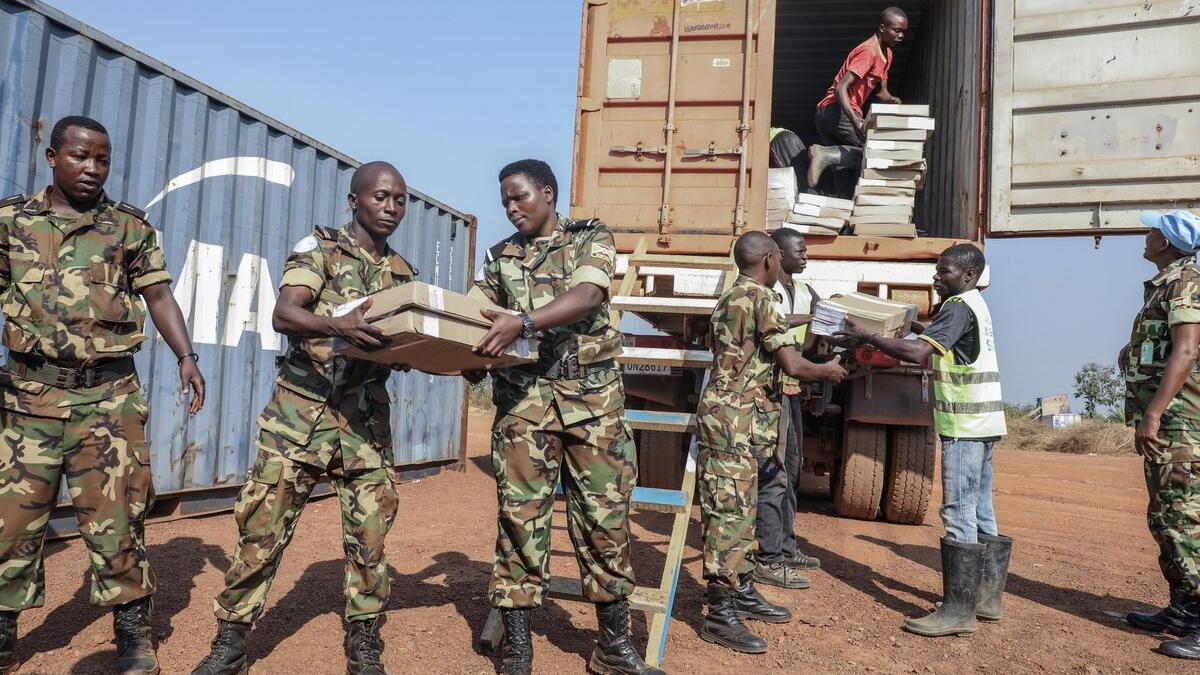 Des Casques bleus transportent des fournitures depuis un véhicule‑conteneur.