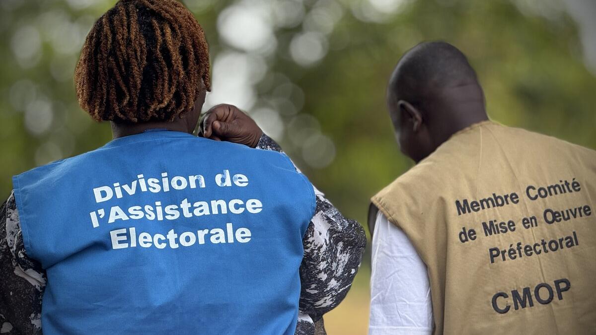 Un représentant porte une veste avec les mots « Division de l’Assistance Électorale ».