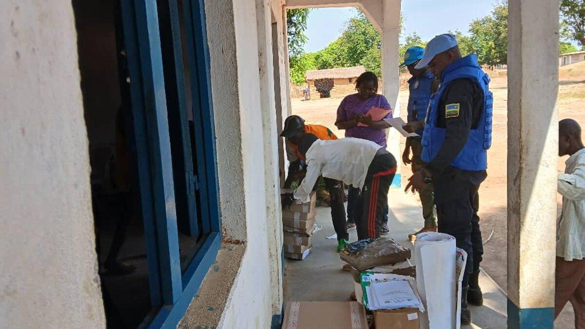 Des représentants trient des fournitures devant un bâtiment. 