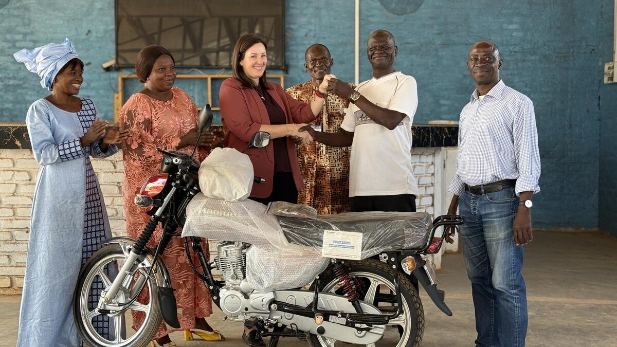 Des représentants posent pour une photo à côté d’une moto. 
