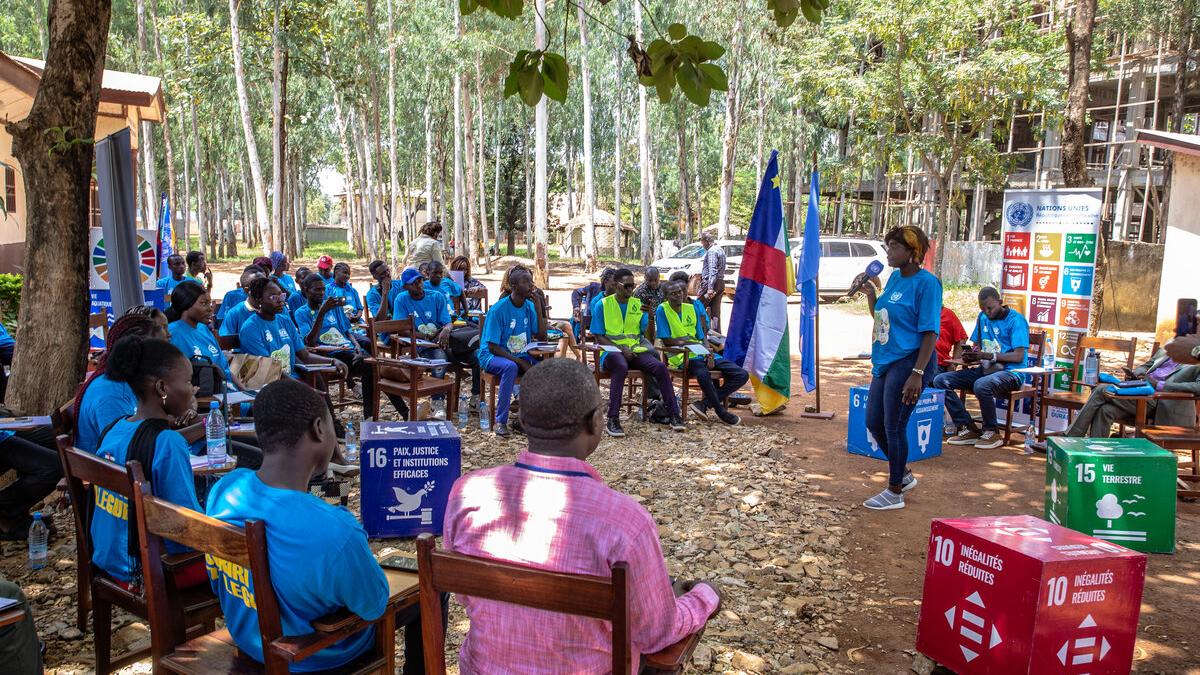 Un groupe écoute un intervenant en plein air.