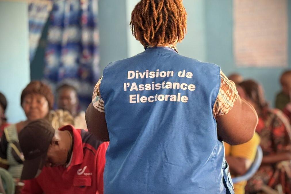 Un représentant porte une veste avec les mots « Division de l’Assistance Électorale ».