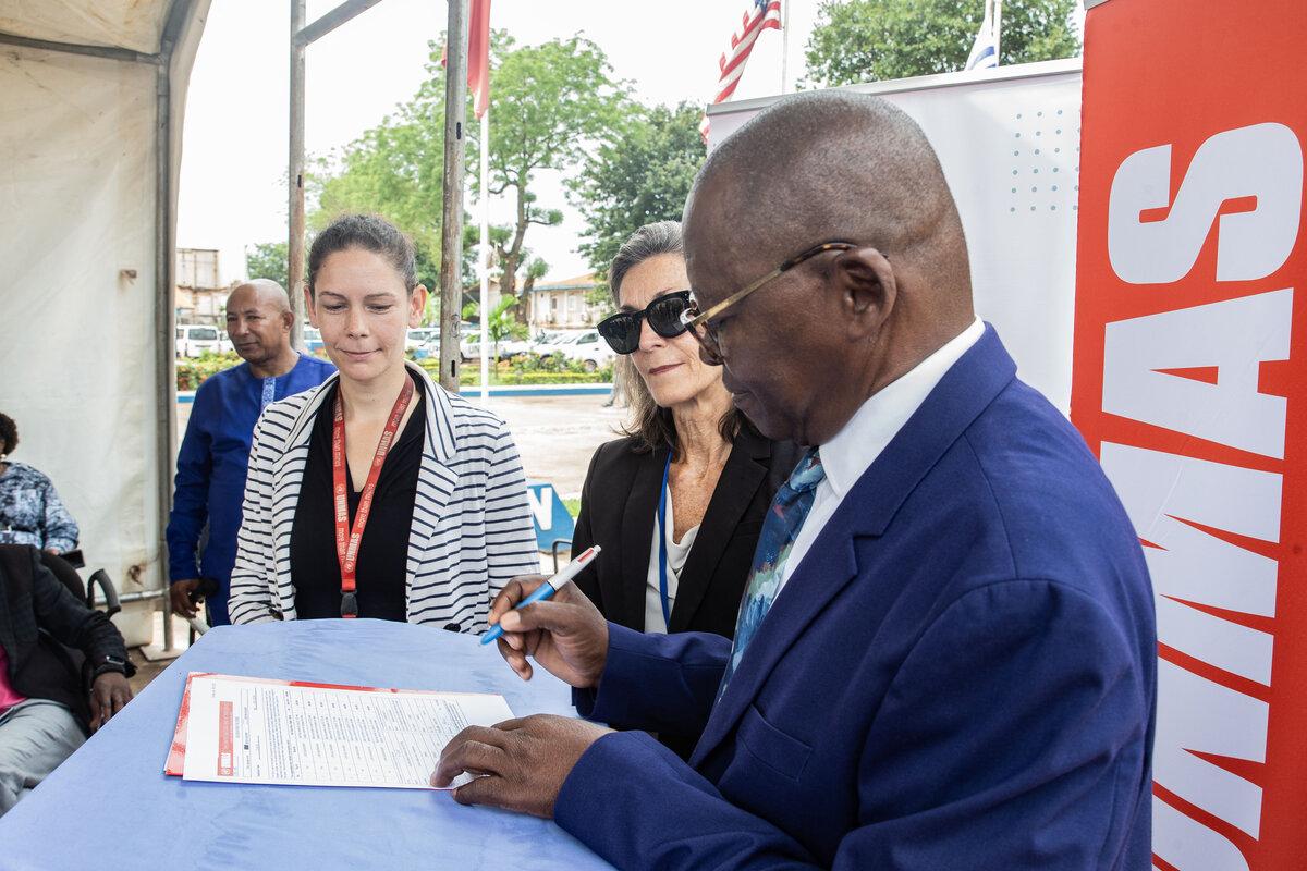 Le président de COMNAT‑ALPC signe un document.
