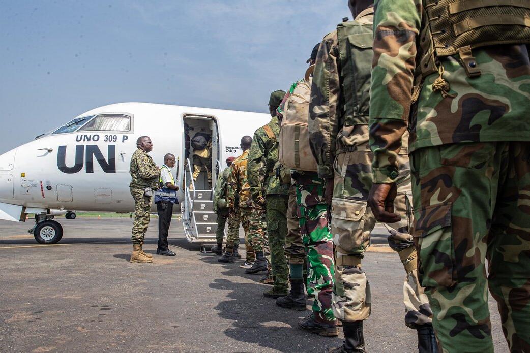 Des Casques bleus font la queue pour monter à bord d’un avion de l’ONU.