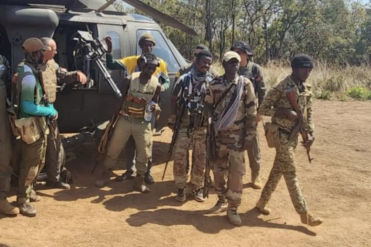 Un groupe de représentants armés se tient à côté d'un hélicoptère.