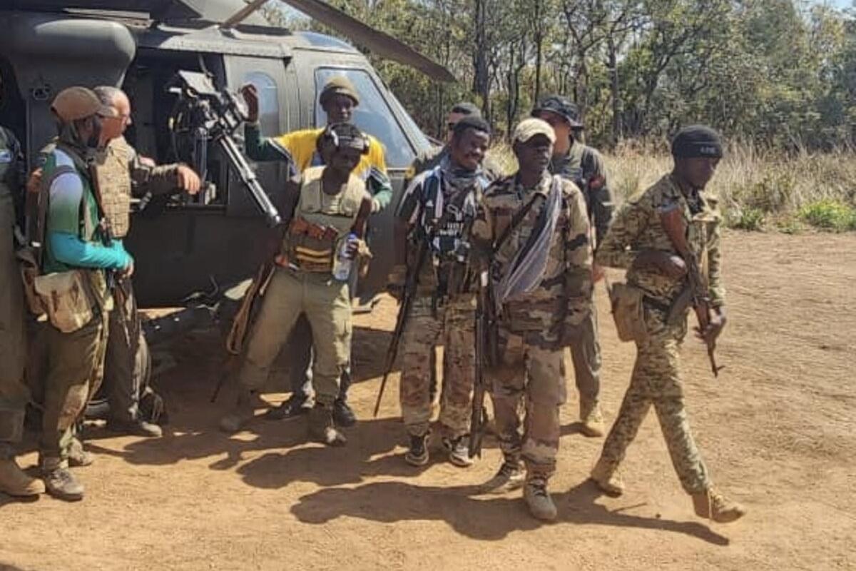 Un groupe de représentants armés se tient à côté d'un hélicoptère.