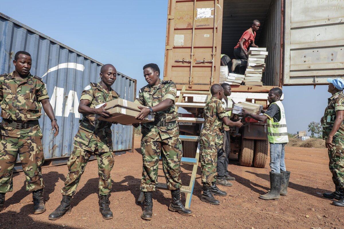 Des Casques bleus transportent des fournitures depuis un véhicule‑conteneur.