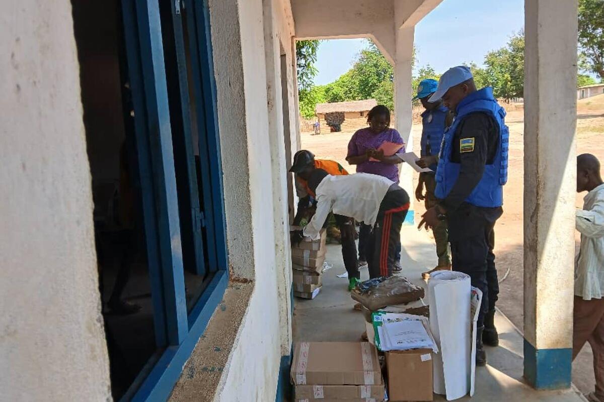 Des représentants trient des fournitures devant un bâtiment. 