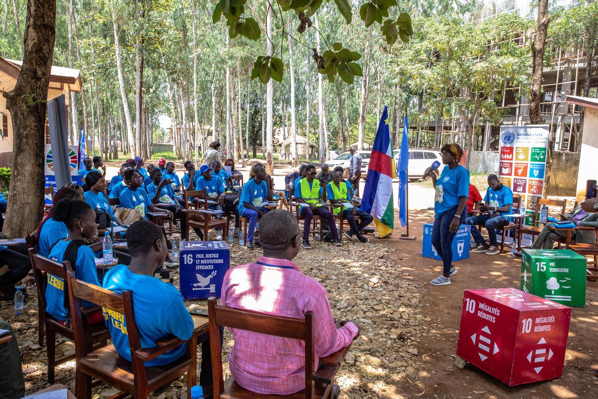 Un groupe écoute un intervenant en plein air. 