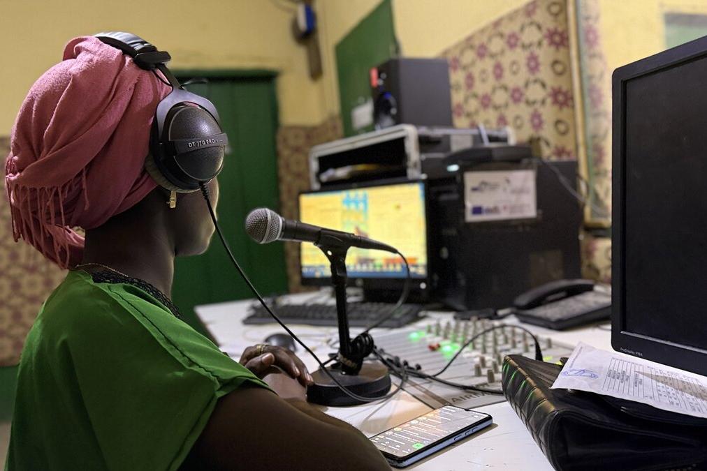 Une personne est photographiée avec un microphone dans un studio d’enregistrement.