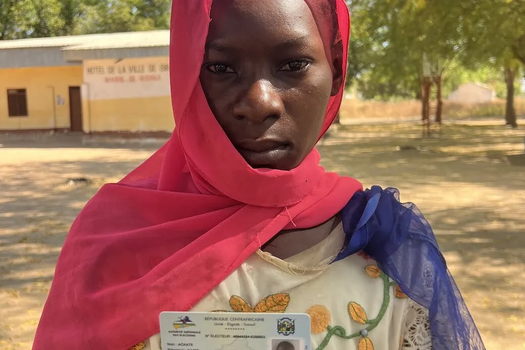 Un électeur pose pour une photo avec sa carte d’identité.