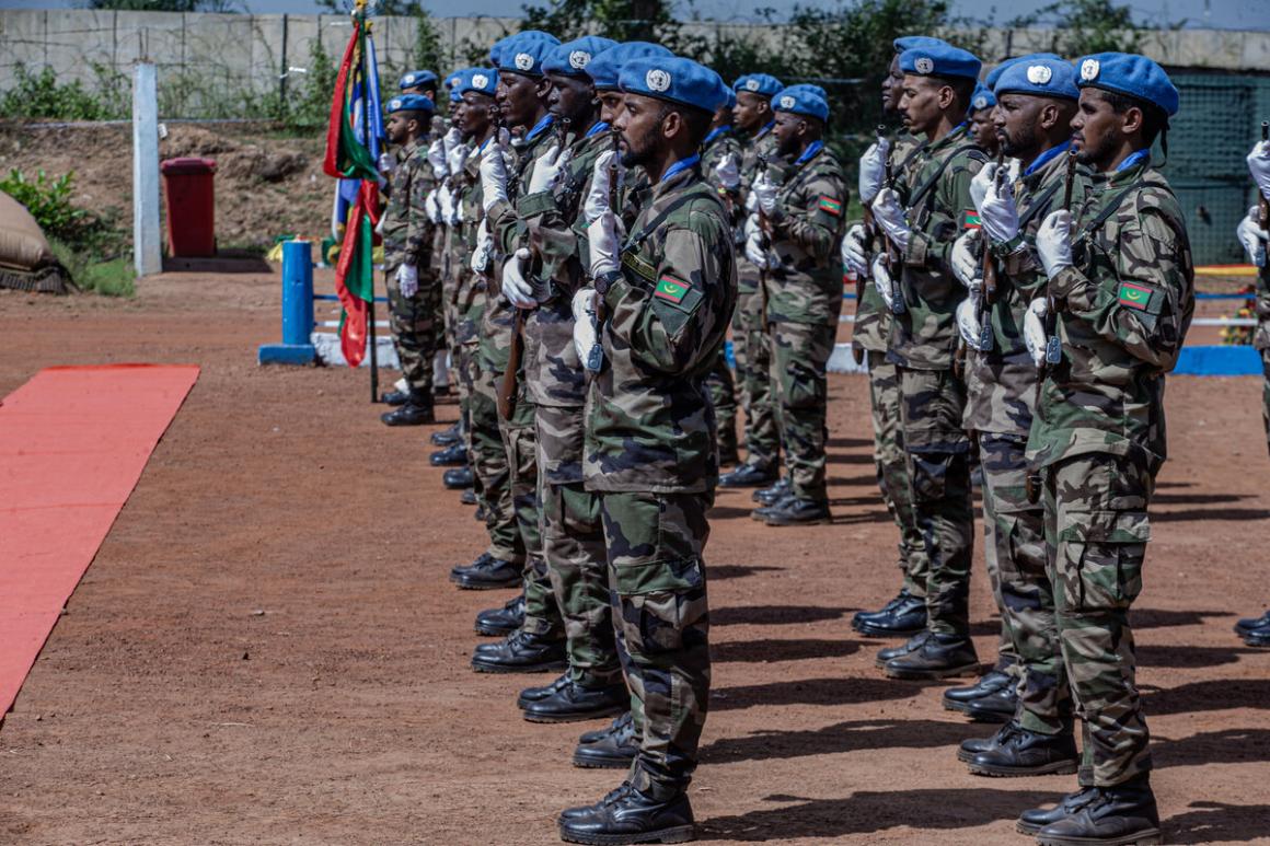 Un groupe de soldats de la paix se tient en rangs serrés et salue.