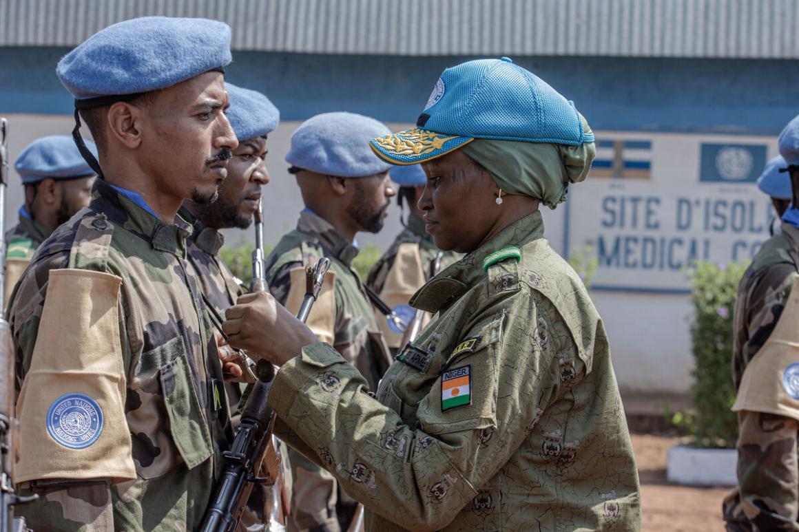 Une Casque bleue en uniforme militaire épingle une médaille sur l'uniforme d'une autre Casque bleue