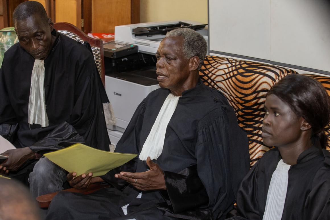 Trois juges sont assis côte à côte et s'adressent à une salle remplie de personnes.