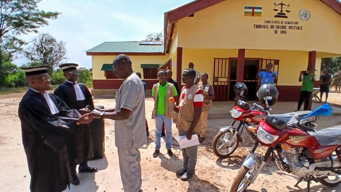 Des personnes discutent avec deux juges devant un nouveau bâtiment