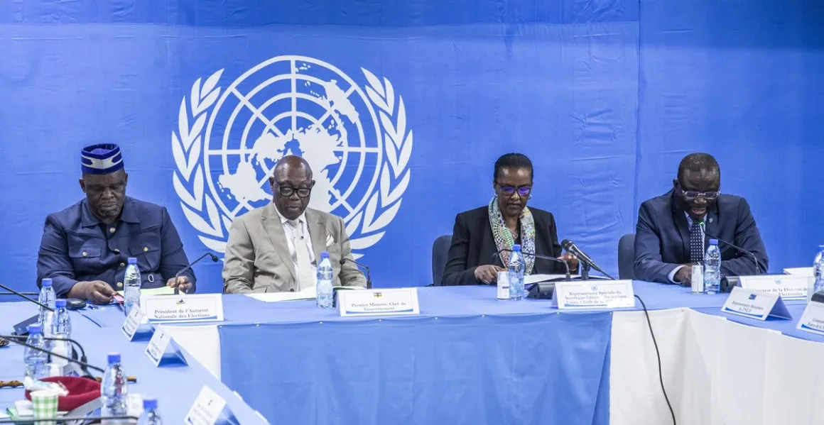 Un groupe de fonctionnaires est assis autour d'une table devant un logo de l'ONU
