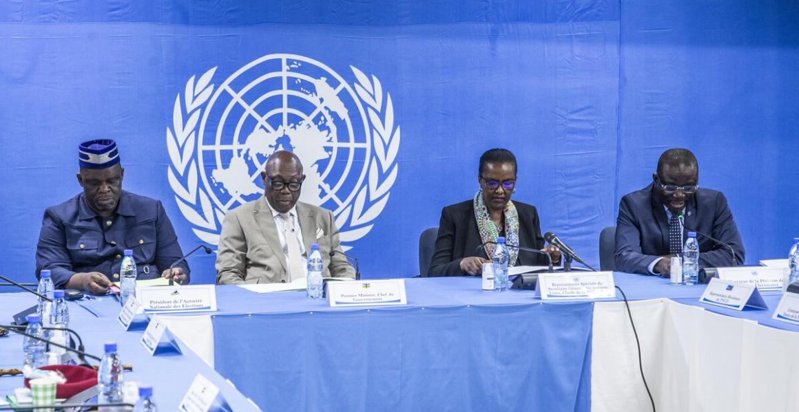 Un groupe de fonctionnaires est assis autour d'une table devant un logo de l'ONU