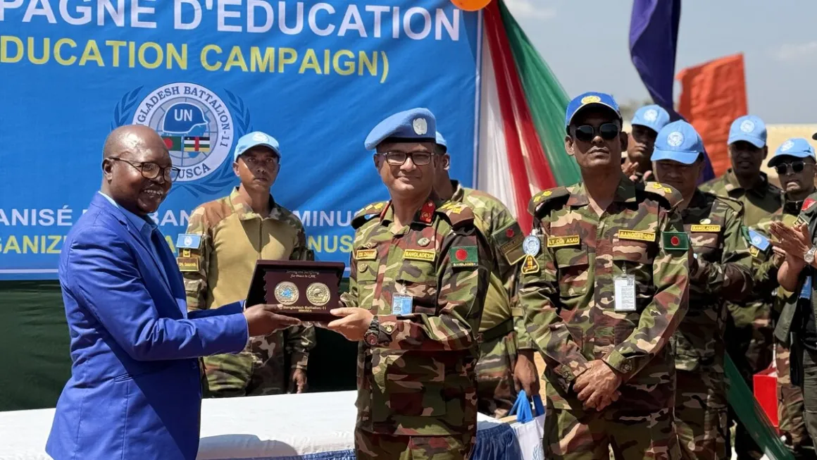 Un homme en costume remet un prix aux Casques bleus