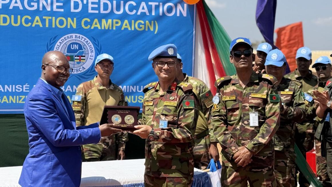 Un homme en costume remet un prix aux Casques bleus