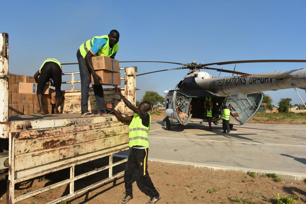 Un groupe d'hommes décharge des cartons devant un hélicoptère