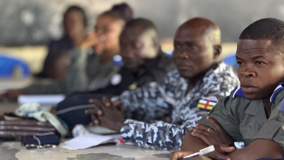 Un groupe de personnes en uniforme est assis en rang à une longue table.