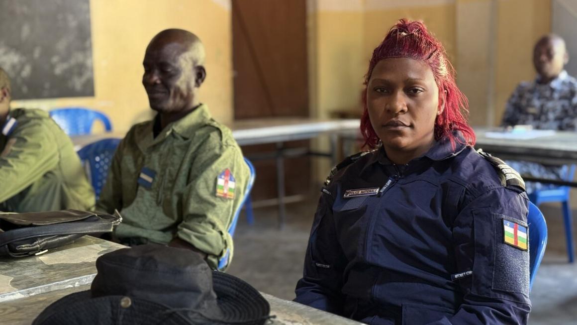 Une femme en uniforme militaire, assise à un bureau, regarde l'objectif.