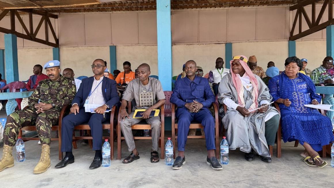 un groupe de personnes assises en rang, vêtues de vêtements civils et militaires
