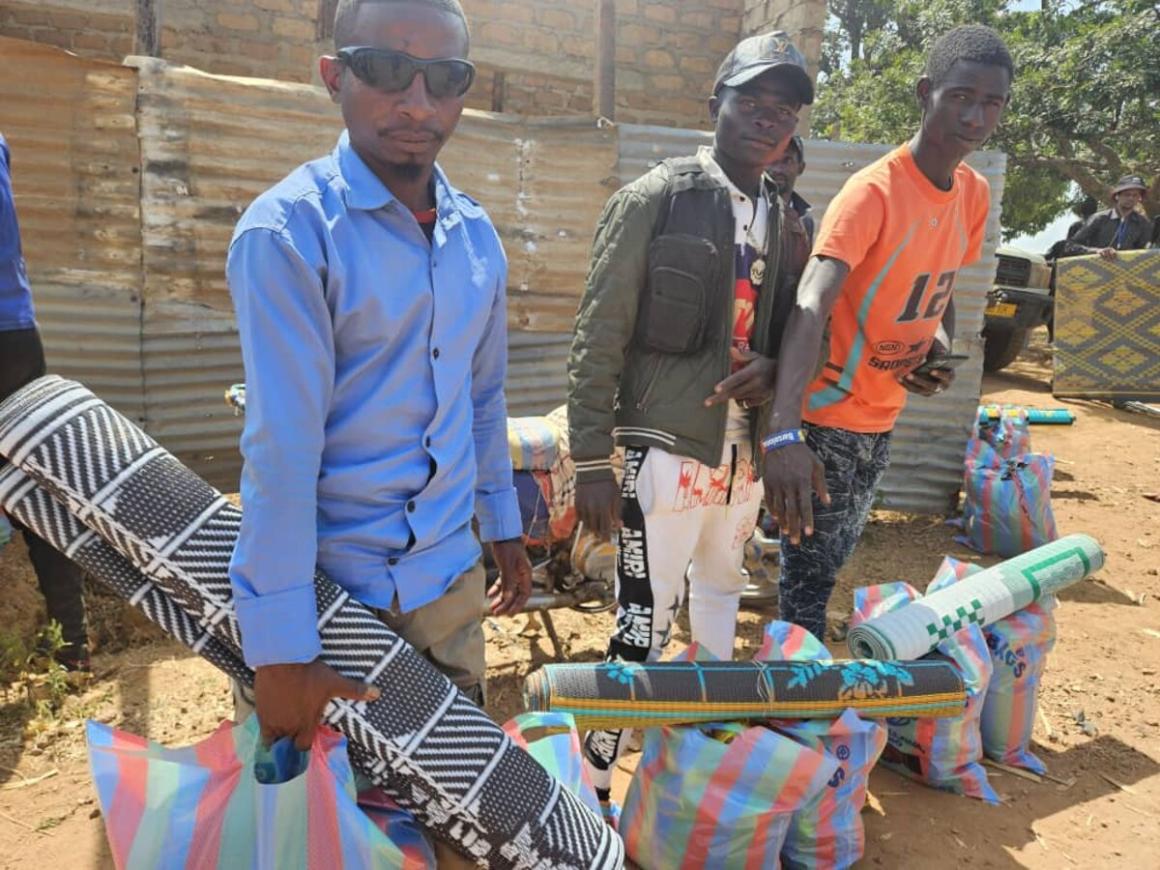 Trois hommes portent des sacs et des tapis roulés.