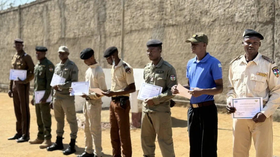 Des hommes en uniforme militaire se tiennent en rang, tenant des certificats.