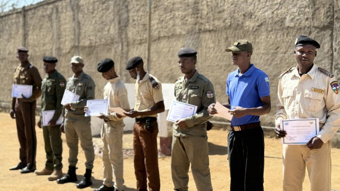 Des hommes en uniforme militaire se tiennent en rang, tenant des certificats.