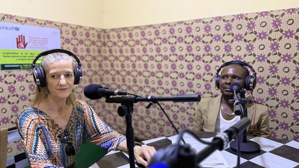 Un homme et une femme sont assis dans un studio, devant des microphones, portant des casques.