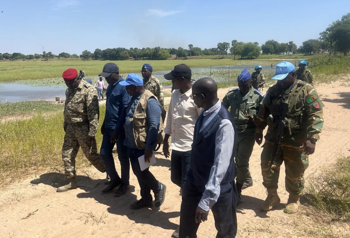 Un groupe de personnes en civil et en militaire marchent dehors en discutant.