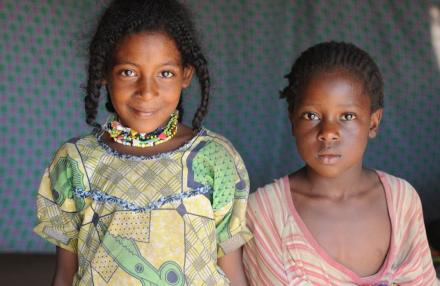 UN personnel stand beside a vehicle near a compound with metal fencing